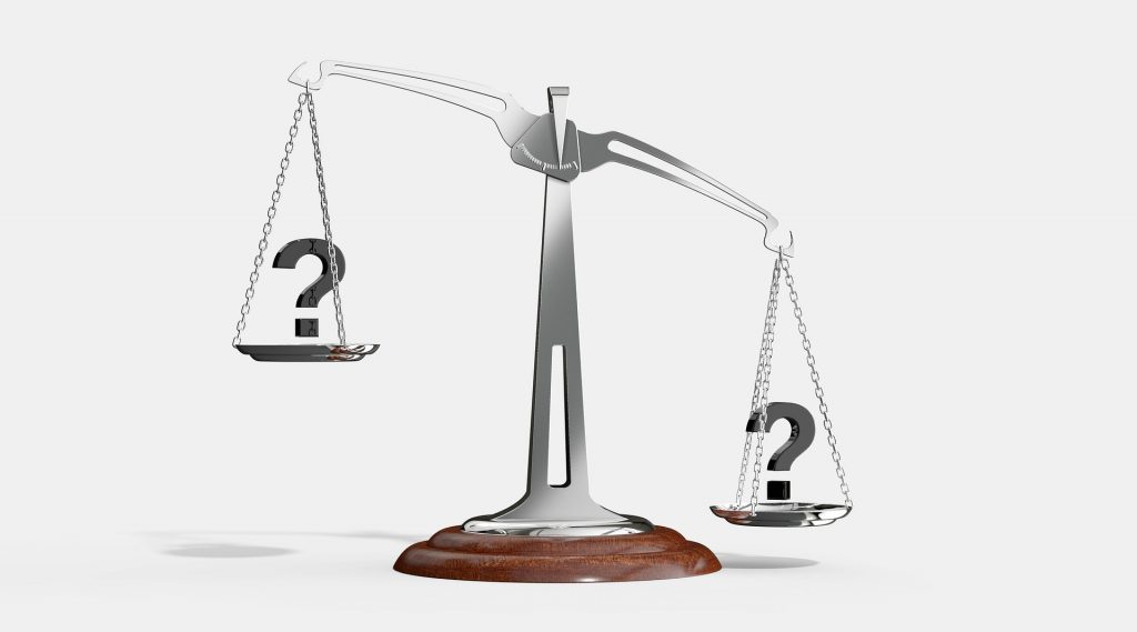 Une balance avec un point d'interrogation sur chaque côté, penche vers la droite.