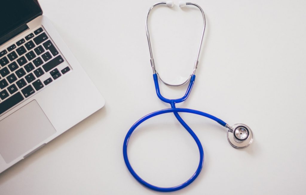 Un stéthoscope est posé au milieu avec un ordinateur portable sur le côté gauche.