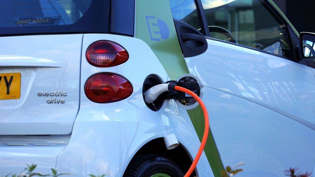 Une voiture blanche est branchée à un câble orange pour recharger.