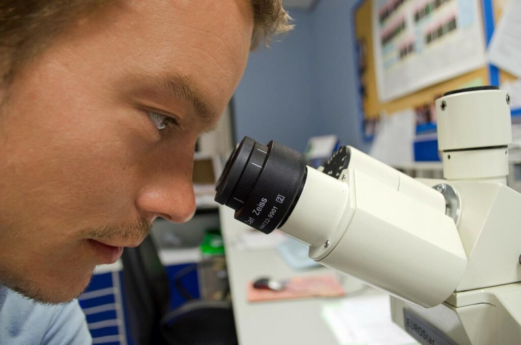 Un homme met ses yeux devant un microscope.