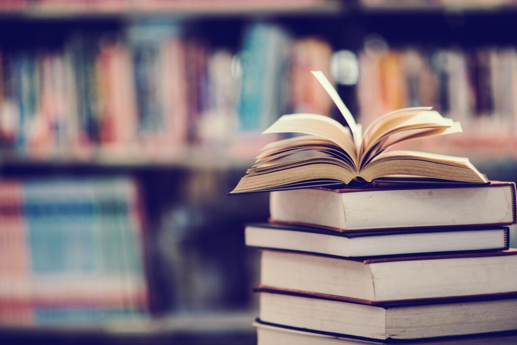 Un livre ouvert sur une pile de livre dans une bibliothèque.