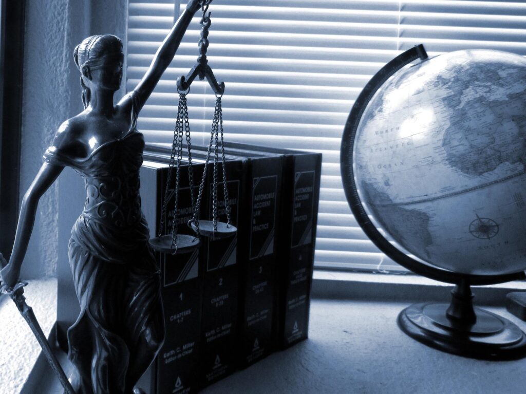 Statue de la justice à côté de livres de droit et d'un globe terrestre.